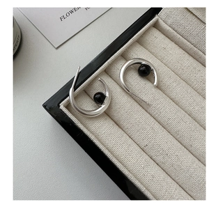 Close-up of S925 sterling silver C-shaped earrings with black agate on a jewelry tray