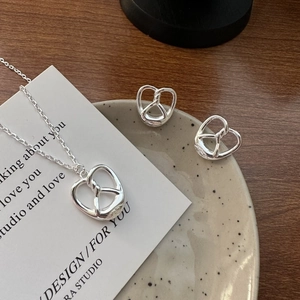 S925 sterling silver pretzel pendant necklace and stud earrings set on a ceramic tray