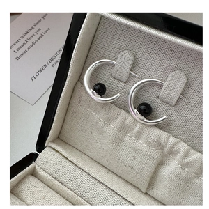 Detailed view of silver S925 C-shaped earrings with black onyx bead in a gift box