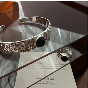 Detailaufnahme von silbernem Armreif und Ring mit gehämmerter Textur und schwarzem Onyx