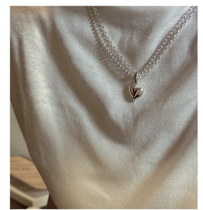 Close-up of double-layer silver beaded chain with a heart pendant on a soft background