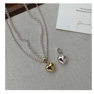 Detail view of double-layer necklace with 925 silver and gold heart-shaped pendants