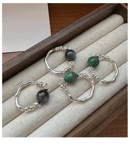 Detailed macro of S925 sterling silver rings with irregular liquid texture and green agates