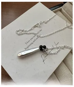 Detail of S925 sterling silver water drop pendant with brushed texture and black beads