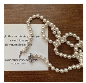 Detail of S925 sterling silver long necklace with glossy white pearls and metal clasp
