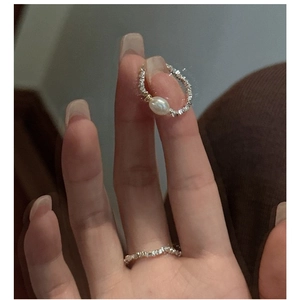 Dettaglio di anelli in argento S925 con texture frantumata e una perla bianca ovale