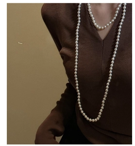 Close-up of elegant S925 silver long pearl necklace on a brown V-neck sweater