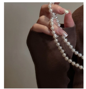 Close-up of S925 silver pearl necklace featuring round white pearls on dark sweater