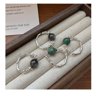 Macro shot of silver stackable rings with emerald and grey cat eye stones on velvet