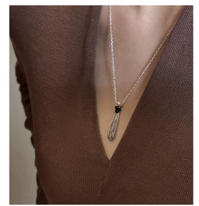 Close-up of S925 sterling silver water drop pendant necklace with black beads on a model