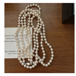 Detail view of long multi-layer white pearl necklace with elegant silver clasp on wood
