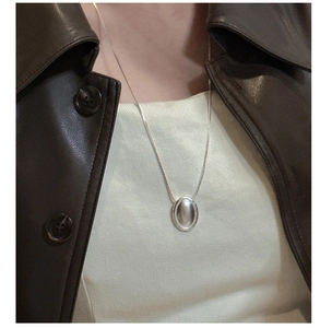 Primo piano della collana in argento sterling con ciondolo ovale su giacca di pelle