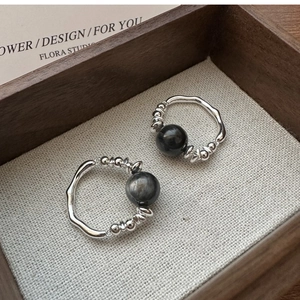 Macro shot of S925 sterling silver beaded rings with dark grey stone on rustic wood