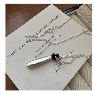 Detail of S925 silver teardrop necklace with hammered texture and black bead accent