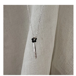 Macro detail of S925 silver teardrop necklace with hammered texture and black beads