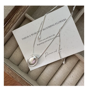 Primo piano di una collana in argento S925 con pendente ovale su porta gioielli