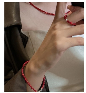 Detail of red bead jewelry set with necklace, bracelet and ring on a model