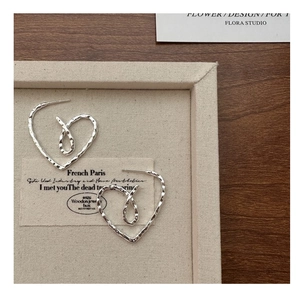 Detailed macro view of S925 sterling silver heart earrings with hammered vintage texture