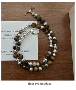 Détail du collier en œil de tigre avec fermoir à bascule argenté sur bois sombre