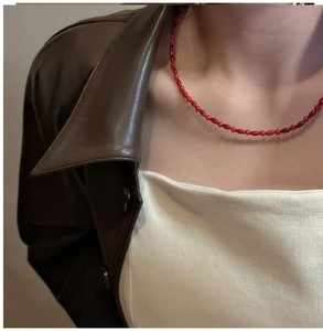 Detail of red beaded necklace with oval accents worn by a model in casual chic outfit
