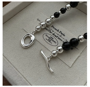 Gros plan détaillé des perles en argent S925 et du collier en agate noire avec fermoir OT
