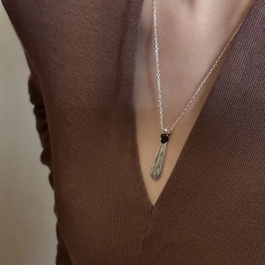 Minimalist S925 sterling silver waterdrop necklace with small black beads on a sweater