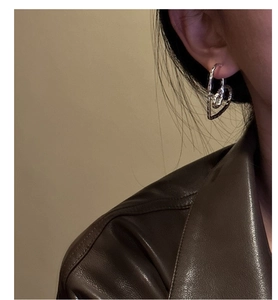 Detail of silver S925 heart earrings with hammered texture on a model wearing leather