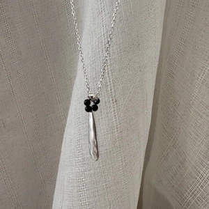 S925 sterling silver teardrop necklace with black beads on textured fabric