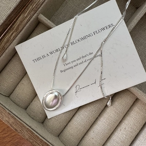 Collana minimalista in argento S925 con ciondolo ovale su scatola portagioie in lino