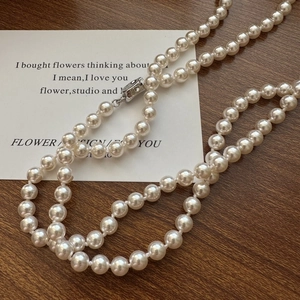 Long S925 sterling silver pearl sweater necklace on a vintage wooden background