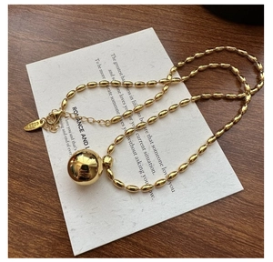 Detail of S925 sterling silver beaded necklace with large gold ball pendant and logo tag