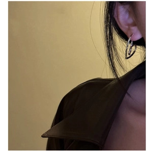 Detail of silver heart-shaped earring with hammered texture worn by a fashion model