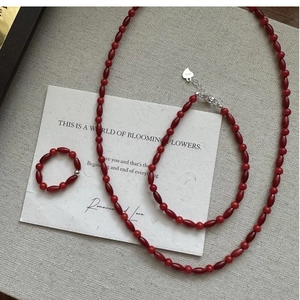 Close-up of S925 sterling silver red bead jewelry set with heart charms on grey fabric