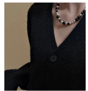 Gros plan d'un collier en argent S925 avec agate noire porté sur un cardigan à col V