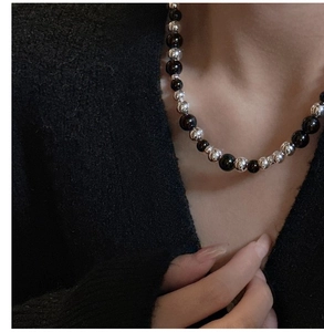 Gros plan sur collier de perles en argent S925 avec agate noire et sphères gravées