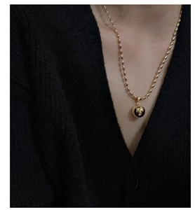 Detailed view of a gold S925 silver necklace with polished beads on a black knit sweater