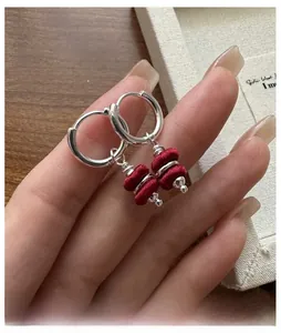 Close-up of S925 silver hoop earrings featuring handmade red thread woven drum charms
