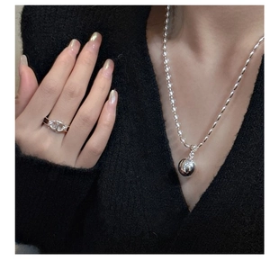 Detail of silver S925 beaded necklace with mirror ball pendant on a model in black