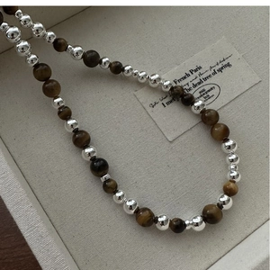 Détail de perles en argent S925 et pierres œil de tigre dans un coffret à bijoux