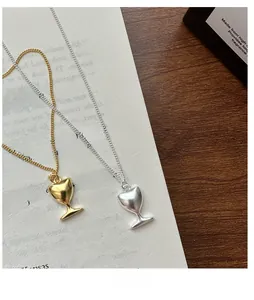 Gros plan de pendentifs gobelet en or et argent sur chaînes O sur fond de papier texturé