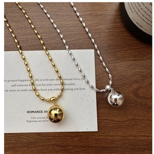 Macro shot of polished silver and gold bead pendant necklace on minimalist art background