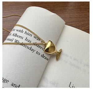 Détail d'un collier pendentif calice doré sur un livre ouvert avec un fond en bois rustique