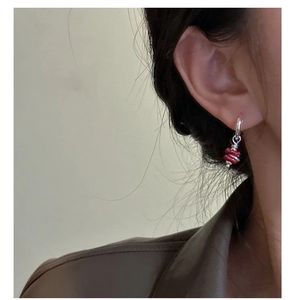 Close-up of S925 silver hoop earrings with textured red beads worn by a model