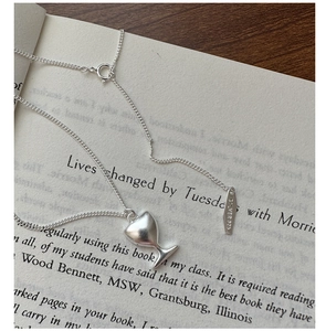 Détail du collier coeur en argent sterling S925 posé sur les pages d'un livre