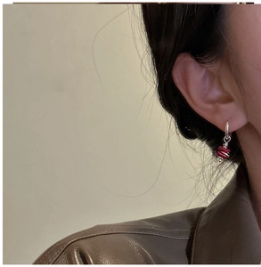 Detailed close-up of S925 silver hoop earrings featuring a textured red bead pendant accessory
