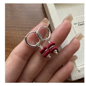 Close-up of S925 sterling silver earrings with red silk thread pendants held by hand
