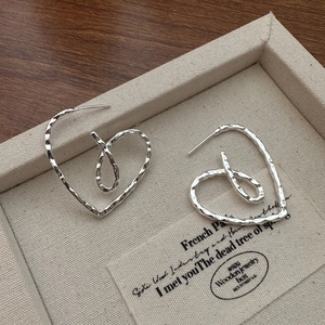 S925 sterling silver heart earrings with hammered texture on a beige jewelry tray
