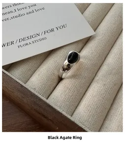 Close-up of minimalist S925 sterling silver ring with oval black onyx on beige jewelry tray