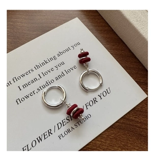 Close-up of S925 silver hoop earrings with dark red fabric beads and delicate texture