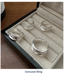 Detail view of silver concave streamline rings and earrings in a beige velvet jewelry box